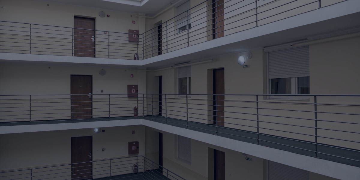 Pátio interno de um prédio residencial, com corredores de vários andares e portas de apartamentos